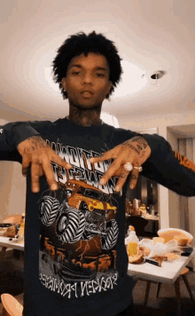 a man wearing a t-shirt with a monster truck on it holds up his hands