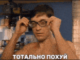 a shirtless man is putting on glasses and making a funny face in a foreign language .