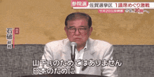a man speaking into a microphone with chinese writing on the bottom right corner