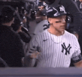 a man in a new york yankees jersey is standing in the dugout .