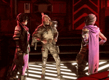 a man in a purple cape is standing next to two women