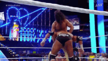 two men are wrestling in a wrestling ring with a heart shaped sign in the background .