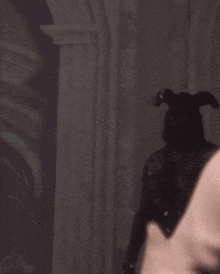 a man with horns on his head stands in front of a pillar