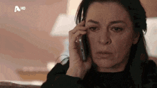 a woman is crying while talking on a cell phone with a hd logo behind her