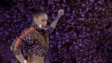 a woman in a crop top is dancing in front of a purple wall .