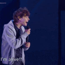 a man in a hoodie says i 'm alive in a dark room