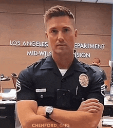 a police officer is standing with his arms crossed in front of a sign that says los angeles mid-wils department vision .