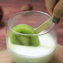 a glass of milk with a slice of kiwi on a stick in it