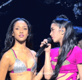 two women are standing next to each other and one is holding a microphone and the name manonstiara is on the bottom right