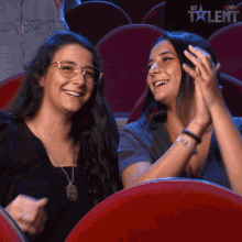 two women are clapping in an auditorium with the words got talent in the background