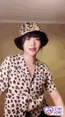 a woman wearing a leopard print shirt and a bucket hat has a sticker that says stay home