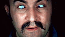 a close up of a man 's face with a mustache and glowing eyes
