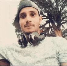 a man wearing headphones and a baseball cap is taking a selfie .