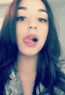 a woman sticking her tongue out while wearing a gray shirt