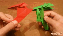 a person is holding a red and a green origami object made by animatica