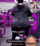 a man is riding an exercise bike in front of a planet fitness sign
