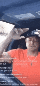 a man is sitting in the passenger seat of a car holding a cell phone .