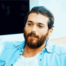 a man with a beard and long hair wears a blue shirt