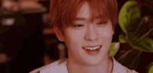 a close up of a young man with red hair smiling and looking at the camera .