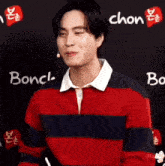 a man in a red and blue striped shirt is standing in front of a sign that says bonch