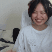 a woman wearing headphones is smiling and wearing a white shirt .