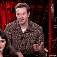 a man in a sweater is sitting in front of a woman and making a funny face