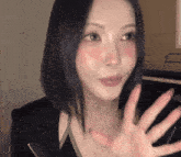 a woman with red cheeks is waving her hand