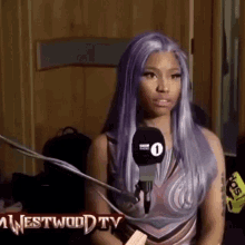 a woman with purple hair is sitting in front of a microphone and talking into it .