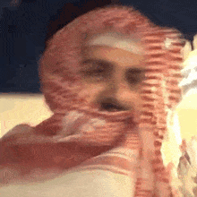 a man wearing a red scarf around his head looks at the camera .