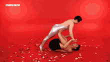 a woman is being lifted in the air by a man on a red background with cosmopolitan.com in the corner
