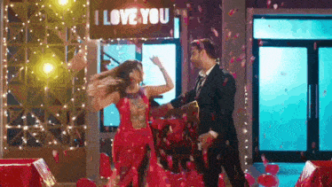 a man and a woman are dancing on a stage with confetti falling around them .