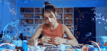 a woman is sitting at a table with a bun on her head and drawing on a piece of paper