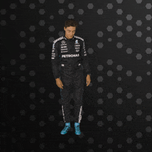 a man in a petronas racing suit is standing in front of a black background