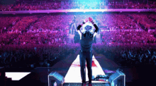 a man is standing on a stage with his hands in the air in front of a crowd