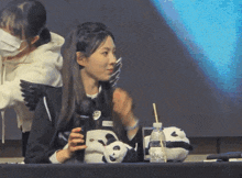 a woman sitting at a table with a panda bear and a bottle of water