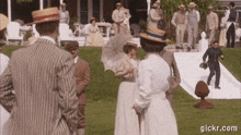 a group of people are standing on a lawn in front of a house .