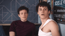two boys are sitting in front of a poster that says sous le vi
