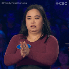 a woman applauds while wearing a badge that says family feud canada