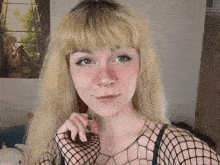 a girl with blonde hair is wearing a fishnet top