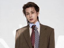 a young man wearing a suit and tie is standing in front of a white background