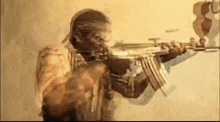 a man in a bandana is holding a gun in his hand .