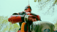 a man in a red and black costume is standing in a park