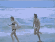 a man and a woman in a bikini are running on the beach