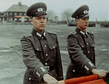 two men in military uniforms with the letter b on their caps