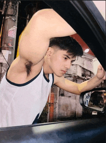 a man in a white tank top is looking out the window of a car