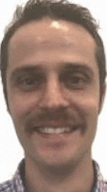 a close up of a man with a mustache smiling .