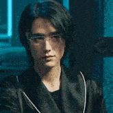a young man wearing glasses and a black robe is smiling .