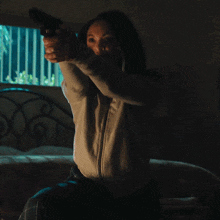 a woman is pointing a gun at the camera