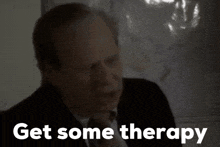 a man in a suit says get some therapy in front of a map