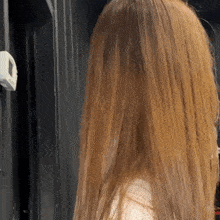 a woman with long blonde hair is standing in front of a door and looking at the camera .